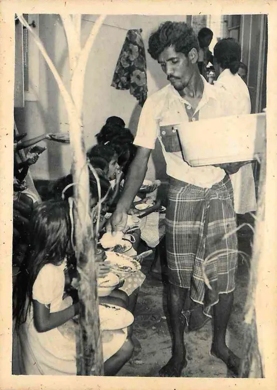 A volunteer serving a meal to children seated on the floor