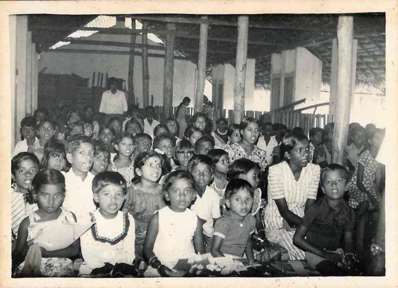A large group of children gathered under an open-sided hall