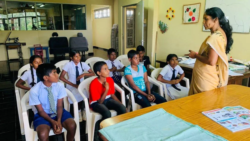 Students in school uniform listening to a teacher during a tuition class