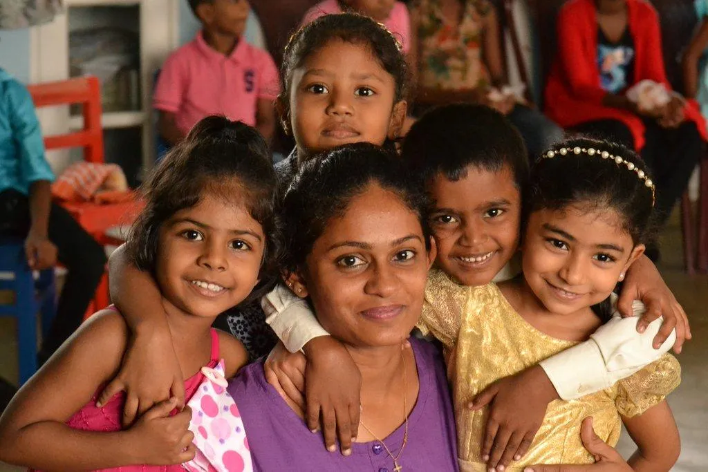 Smiling young girls hugging their teacher in a Montessori classroom
