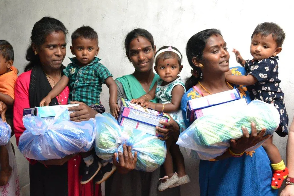 Mothers holding their young children and nutrition packs