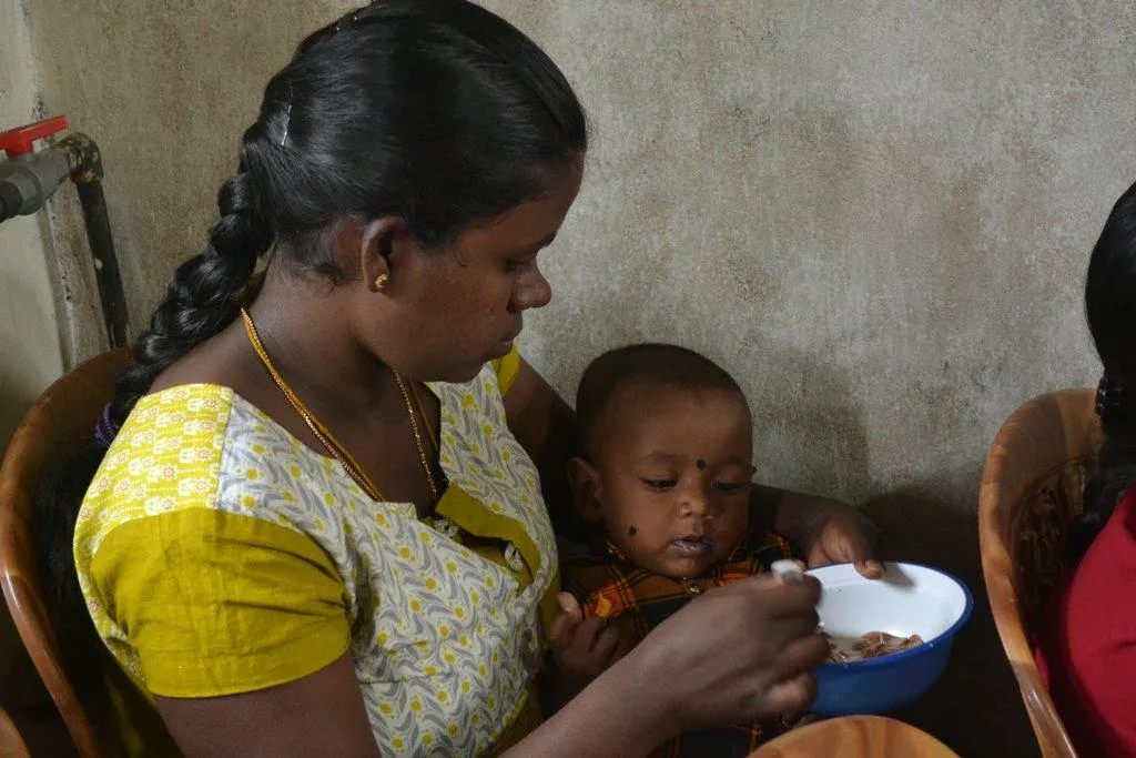 A mother feeding her baby from a bowl