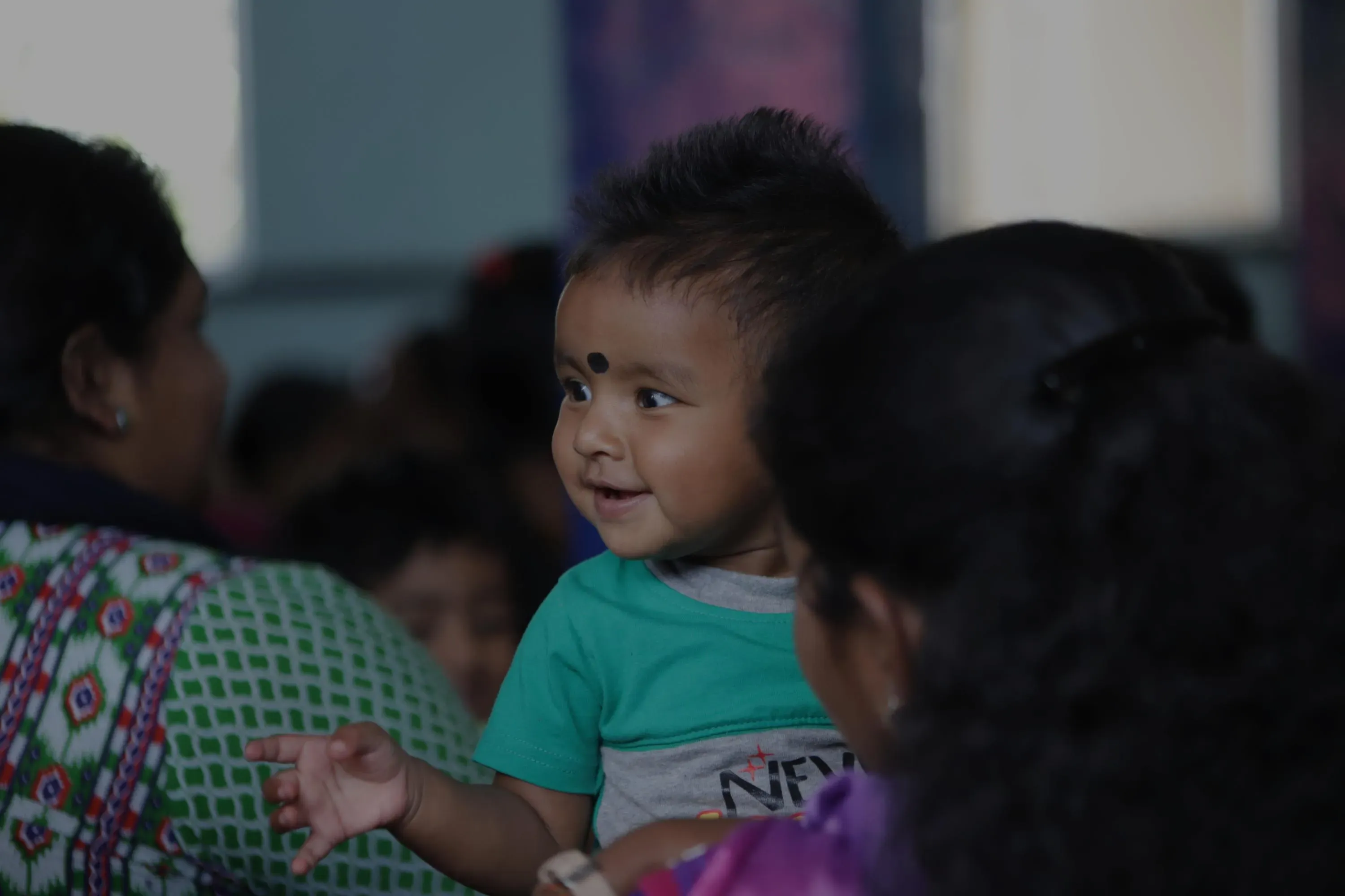 A smiling toddler held by his mother at a Word & Deed gathering